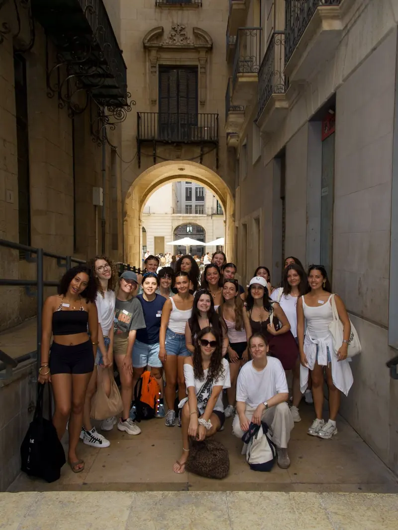 Community group photo under a stone arch in Alicante