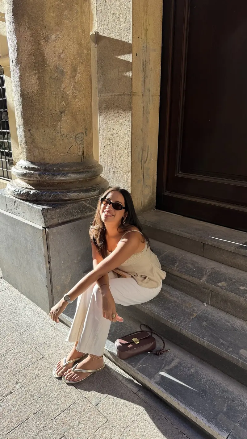 Shely Palomino smiling in sunglasses, sitting on sunny stone steps